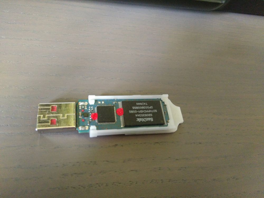 Die Abbildung zeigt einen geöffneten USB-Stick. Auf den silbernen Verlötungen von zwei schwarzen Chips ist jeweils ein Punkt Siegellack aufgetragen.